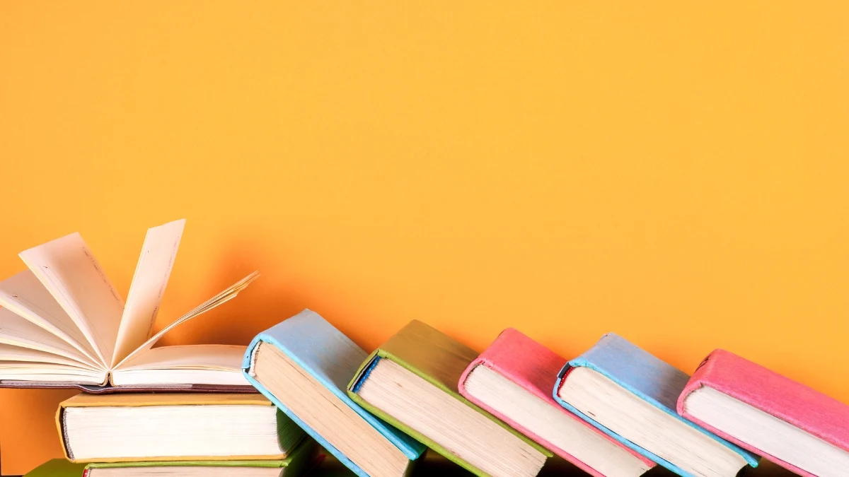 Pilha de livros coloridos sobre fundo laranja